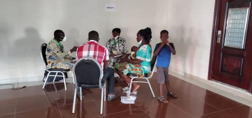 A nursing mother, Dedesi Nyanyegbe Aimee, participating in a group work session while breastfeeding her child.)]
